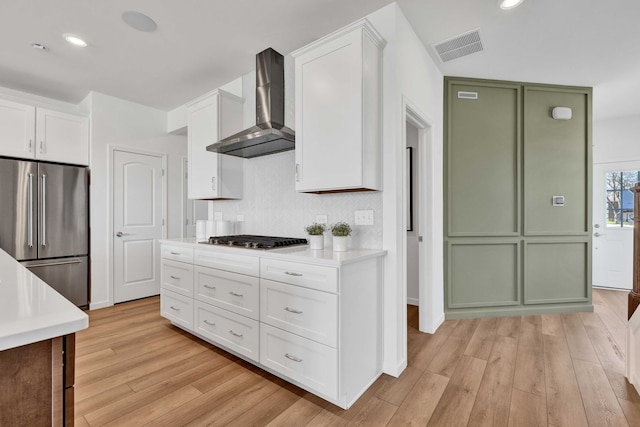 1063 Houston St Unit 89005, Batavia, IL 60510 - kitchen with appliances with stainless steel finishes, wall chimney range hood, green cabinets, light wood-style floors, and light countertops