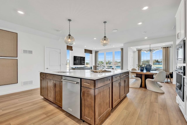1063 Houston St Unit 89005, Batavia, IL 60510 - kitchen featuring stainless steel appliances, light wood-style floors, a kitchen island with sink, a chandelier, and light countertops