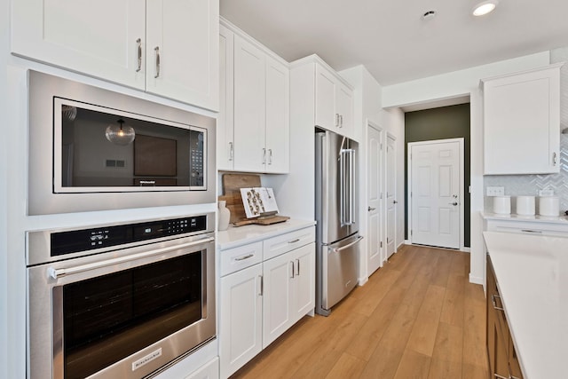 1063 Houston St Unit 89005, Batavia, IL 60510 - kitchen featuring appliances with stainless steel finishes, light wood-style floors, decorative backsplash, white cabinets, and light countertops