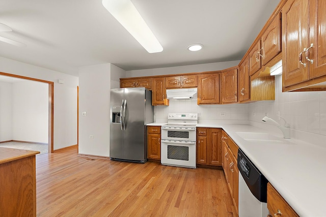 10509 San Luis Ln, Orland Park, IL 60467 - kitchen featuring appliances with stainless steel finishes, under cabinet range hood, brown cabinetry, light wood finished floors, and backsplash
