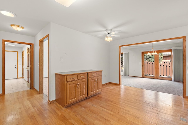 10509 San Luis Ln, Orland Park, IL 60467 - kitchen featuring light wood-type flooring, a ceiling fan, light countertops, pendant lighting, and a chandelier