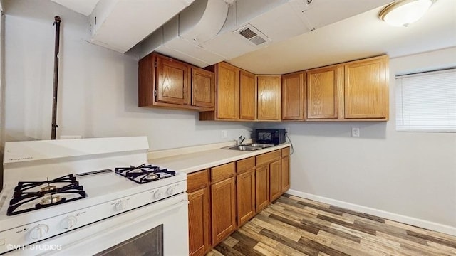 5041 W Fletcher St, Chicago, IL 60641 - kitchen with white range with gas cooktop, light wood-type flooring, light countertops, and brown cabinets