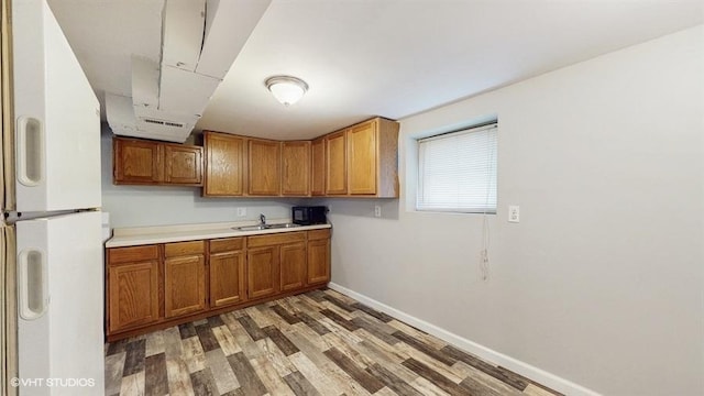 5041 W Fletcher St, Chicago, IL 60641 - kitchen with freestanding refrigerator, brown cabinetry, light wood-type flooring, light countertops, and black microwave