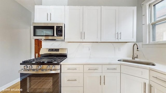 5041 W Fletcher St, Chicago, IL 60641 - kitchen featuring appliances with stainless steel finishes, white cabinetry, wood finished floors, and backsplash