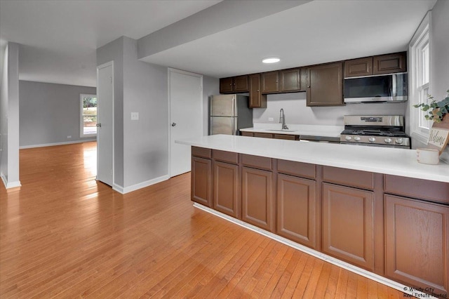 1718 Ardwick Dr, Hoffman Estates, IL 60169 - kitchen with stainless steel appliances, light wood-type flooring, light countertops, a peninsula, and dark brown cabinetry