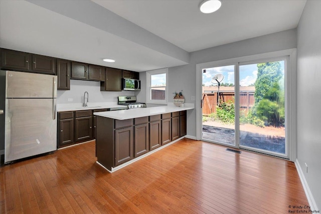 1718 Ardwick Dr, Hoffman Estates, IL 60169 - kitchen featuring appliances with stainless steel finishes, a peninsula, light wood-style floors, and light countertops
