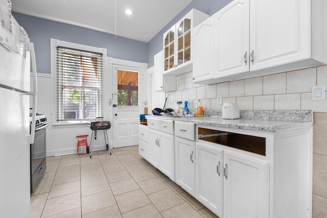 844 Haskell Ave, Rockford, IL 61103 - kitchen with freestanding refrigerator, white cabinetry, glass insert cabinets, range, and light tile patterned flooring