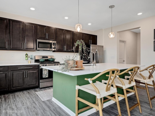257 Kennedy Dr, Saint Charles, IL 60175 - kitchen featuring stainless steel appliances, a breakfast bar, light countertops, light wood-style flooring, and hanging light fixtures