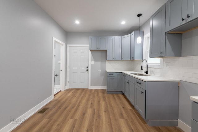 8007 S Avalon Ave, Chicago, IL 60619 - kitchen with gray cabinets, backsplash, light wood-type flooring, recessed lighting, and decorative light fixtures
