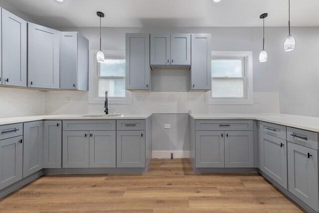 8007 S Avalon Ave, Chicago, IL 60619 - kitchen with gray cabinetry, decorative backsplash, decorative light fixtures, light wood-style flooring, and light countertops