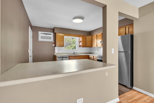 7952 Madison St Unit 2E, River Forest, IL 60305 - kitchen with appliances with stainless steel finishes, a wall mounted AC, light wood finished floors, backsplash, and light countertops
