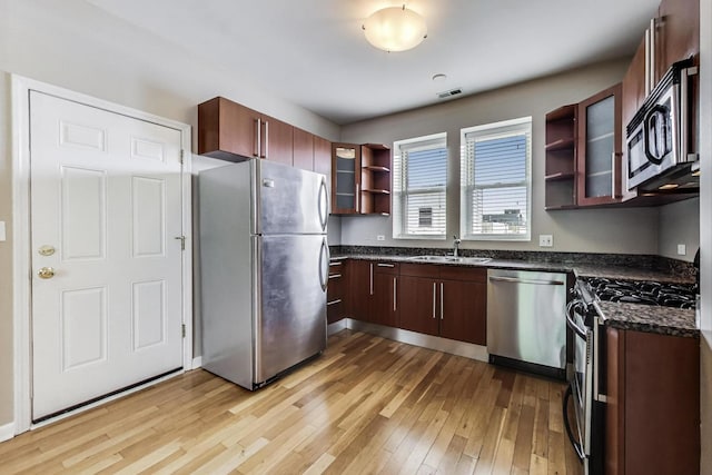 3109 W Argyle St Unit 3, Chicago, IL 60625 - kitchen with stainless steel appliances, light wood-style floors, open shelves, glass insert cabinets, and dark stone countertops