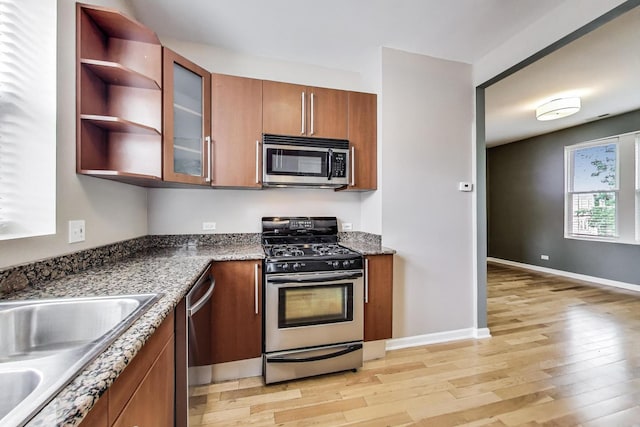 3109 W Argyle St Unit 3, Chicago, IL 60625 - kitchen with appliances with stainless steel finishes, brown cabinetry, light wood-style floors, and glass insert cabinets