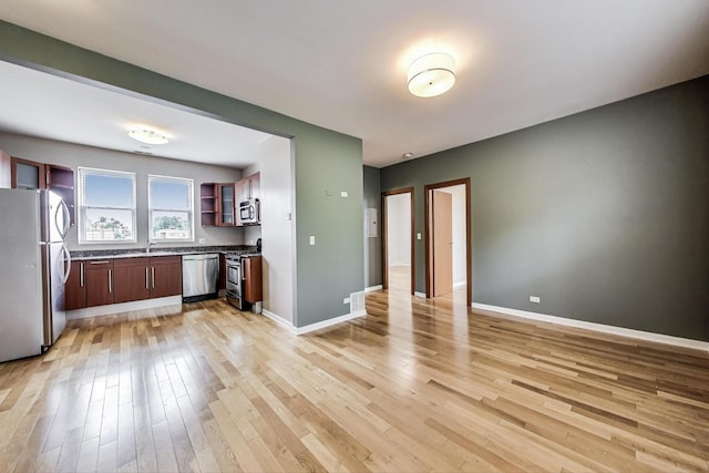 3109 W Argyle St Unit 3, Chicago, IL 60625 - kitchen featuring appliances with stainless steel finishes, open shelves, light wood-style floors, and dark countertops