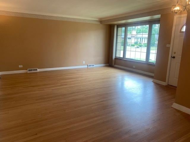 10900 S Tripp Ave, Oak Lawn, IL 60453 - spare room with ornamental molding, light wood-type flooring, and a chandelier
