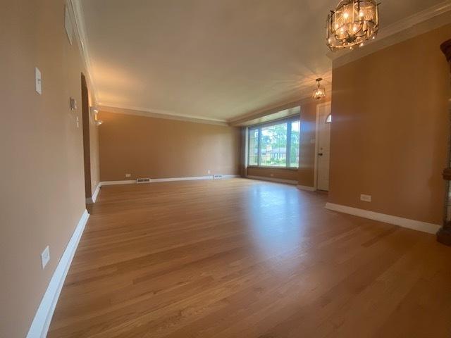 10900 S Tripp Ave, Oak Lawn, IL 60453 - spare room featuring crown molding, wood finished floors, and a chandelier