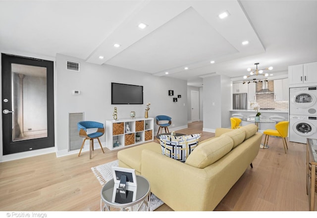 1030 N State St Unit 21K, Chicago, IL 60610 - living area featuring stacked washing machine and dryer, recessed lighting, light wood-type flooring, and a chandelier