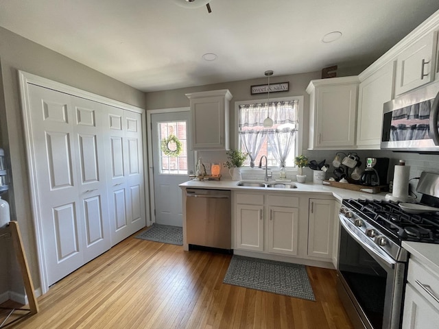1110 Pike St, Peru, IL 61354 - kitchen featuring appliances with stainless steel finishes, light wood finished floors, light countertops, hanging light fixtures, and white cabinetry
