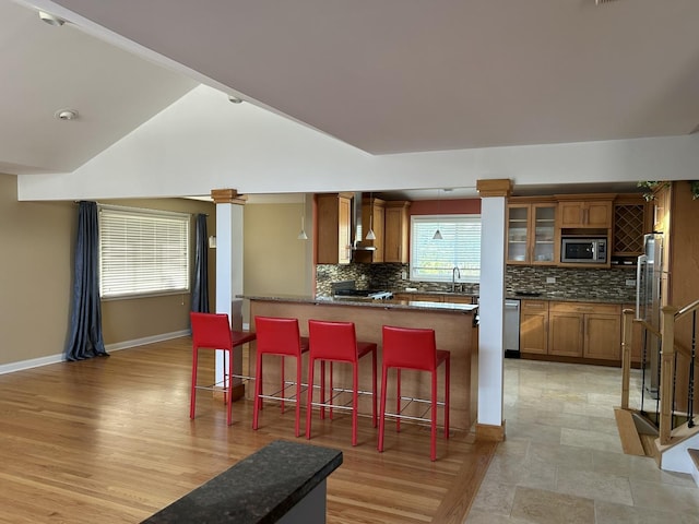 9842 S 88th Ave, Palos Hills, IL 60465 - kitchen featuring appliances with stainless steel finishes, brown cabinets, a peninsula, backsplash, and vaulted ceiling