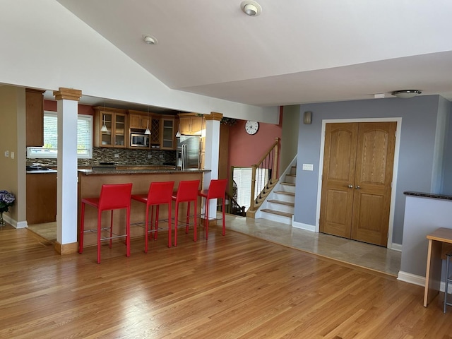 9842 S 88th Ave, Palos Hills, IL 60465 - kitchen featuring stainless steel appliances, light wood-style floors, tasteful backsplash, a kitchen bar, and lofted ceiling