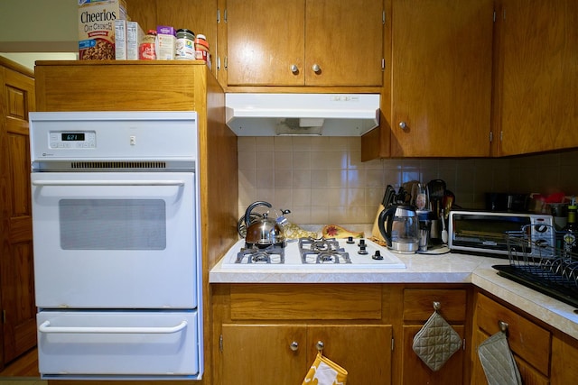 4444 N Central Ave Unit 2W, Chicago, IL 60630 - kitchen with white appliances, under cabinet range hood, a warming drawer, brown cabinetry, and light countertops