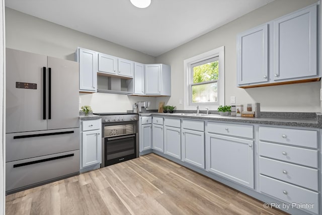 2213 Elm St, Rockford, IL 61102 - kitchen with high end white refrigerator, light wood-type flooring, dark countertops, stainless steel range with electric stovetop, and cooktop