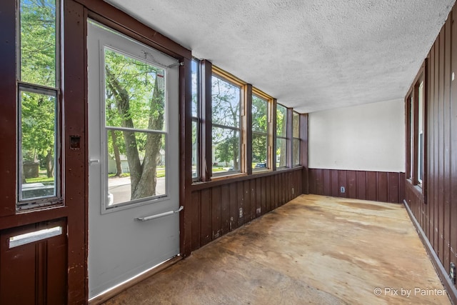 2213 Elm St, Rockford, IL 61102 - unfurnished sunroom with a textured ceiling, wood walls, and concrete floors