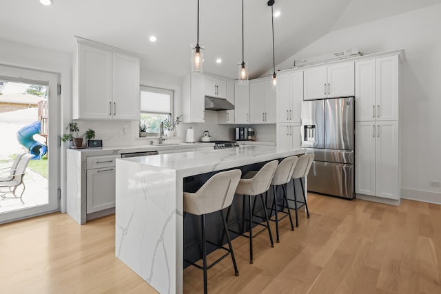 4944 Jarvis Ave, Skokie, IL 60077 - kitchen with stainless steel appliances, under cabinet range hood, decorative backsplash, a kitchen island, and lofted ceiling