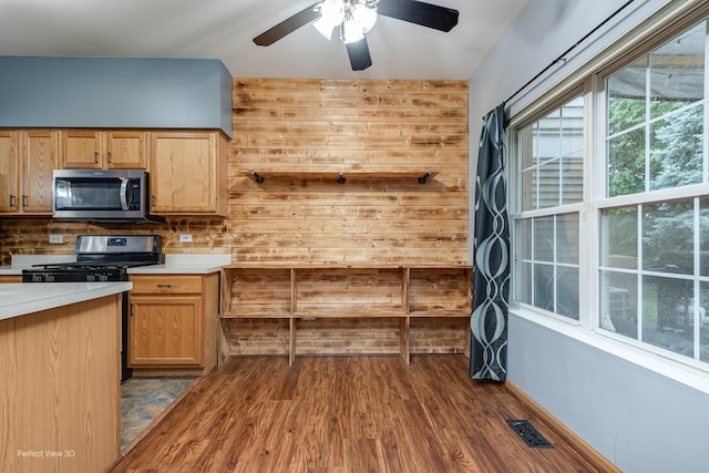 2517 Oak Tree Ln, Plainfield, IL 60586 - kitchen with stainless steel microwave, range, dark wood-style floors, wooden walls, and ceiling fan