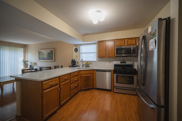 510 Orchards Pass, Bartlett, IL 60103 - kitchen with stainless steel appliances, a peninsula, brown cabinetry, and light wood-type flooring