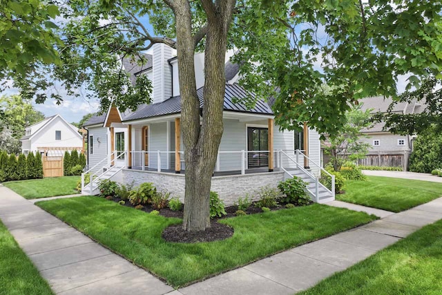 1100 Washington St, Glenview, IL 60025 - view of front of house with a standing seam roof, a porch, a metal roof, and stone siding