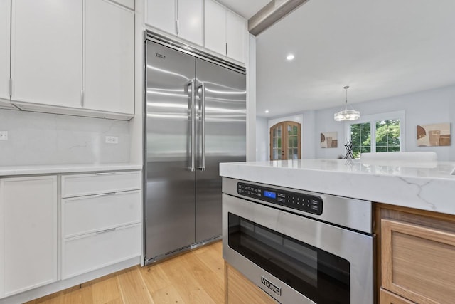 1100 Washington St, Glenview, IL 60025 - kitchen featuring stainless steel appliances, white cabinetry, light wood-style flooring, recessed lighting, and light stone countertops