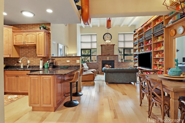 110 N 2nd St Unit 4, West Dundee, IL 60118 - kitchen featuring a kitchen breakfast bar, light wood finished floors, a brick fireplace, beamed ceiling, and open floor plan