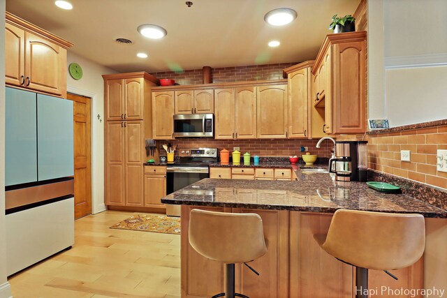 110 N 2nd St Unit 4, West Dundee, IL 60118 - kitchen featuring appliances with stainless steel finishes, a peninsula, a breakfast bar, dark stone countertops, and tasteful backsplash