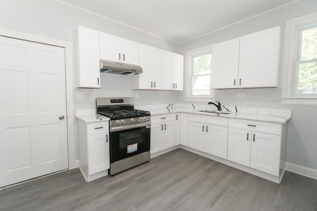 328 Silver St, Elgin, IL 60123 - kitchen with stainless steel gas stove, under cabinet range hood, light wood finished floors, white cabinets, and crown molding