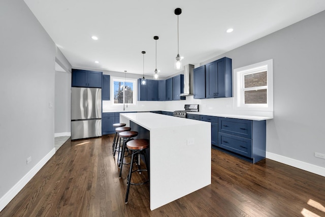 2613 Kenilworth Ave, Berwyn, IL 60402 - kitchen featuring appliances with stainless steel finishes, blue cabinets, a kitchen breakfast bar, light countertops, and dark wood-type flooring
