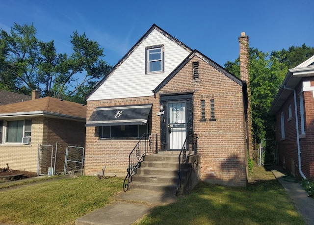 15734 Marshfield Ave, Harvey, IL 60426 - tudor home featuring brick siding, a chimney, a gate, and cooling unit