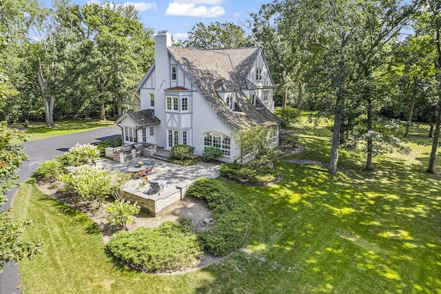 1755 Sunset Ln, Bannockburn, IL 60015 - view of side of home featuring stucco siding, a chimney, a lawn, a patio, and view of wooded area