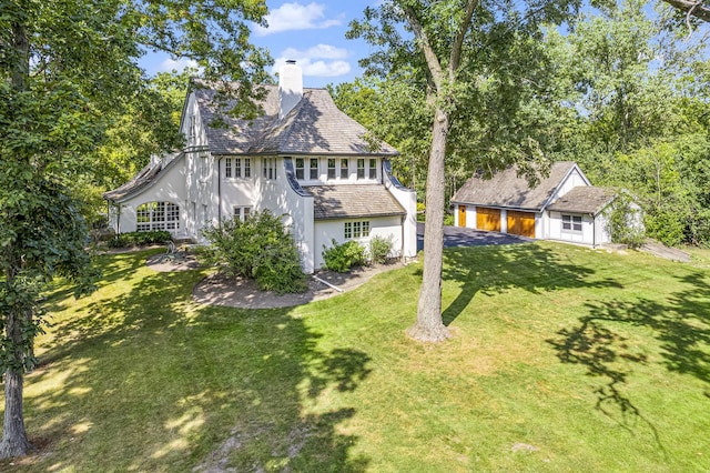 1755 Sunset Ln, Bannockburn, IL 60015 - view of front of house featuring stucco siding, a chimney, a front lawn, an outbuilding, and driveway