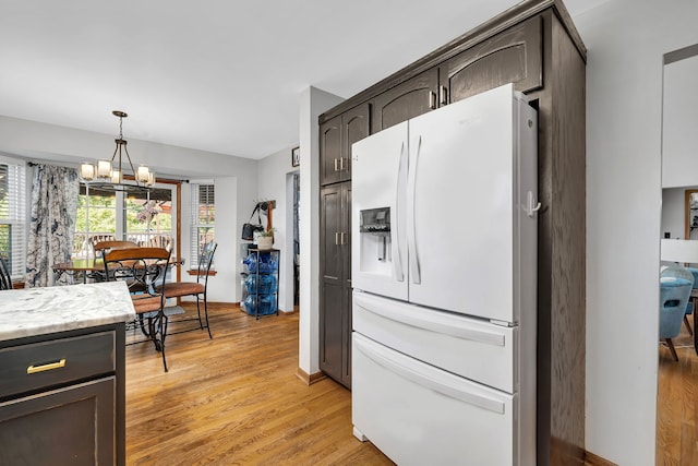 2570 Cobblestone Ct, Morris, IL 60450 - kitchen with white fridge with ice dispenser, a chandelier, light wood-style floors, dark brown cabinetry, and pendant lighting