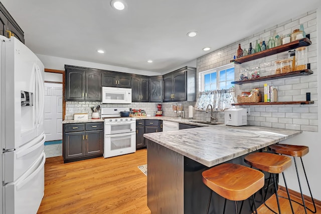 2570 Cobblestone Ct, Morris, IL 60450 - kitchen with white appliances, decorative backsplash, a peninsula, light wood finished floors, and a kitchen bar