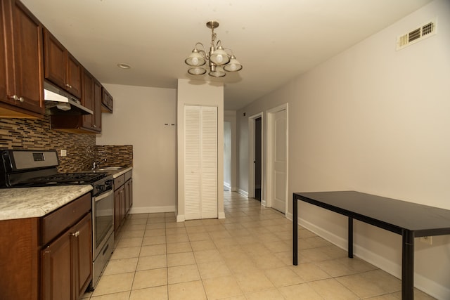 2745 S Sawyer Ave, Chicago, IL 60623 - kitchen with stainless steel gas range oven, under cabinet range hood, a chandelier, tasteful backsplash, and light countertops