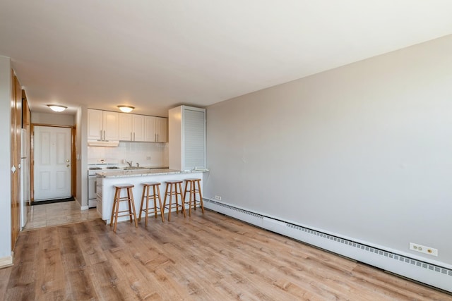 5975 N Odell Ave Unit 4F, Chicago, IL 60631 - kitchen with white gas stove, a baseboard radiator, light wood-type flooring, and a kitchen breakfast bar