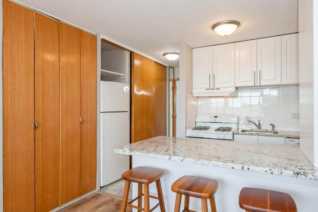 5975 N Odell Ave Unit 4F, Chicago, IL 60631 - kitchen featuring white appliances, under cabinet range hood, a kitchen bar, light stone countertops, and tasteful backsplash