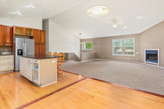 25612 W Woodlawn Ave, Antioch, IL 60002 - kitchen with stainless steel fridge, lofted ceiling, open floor plan, a kitchen breakfast bar, and dark countertops
