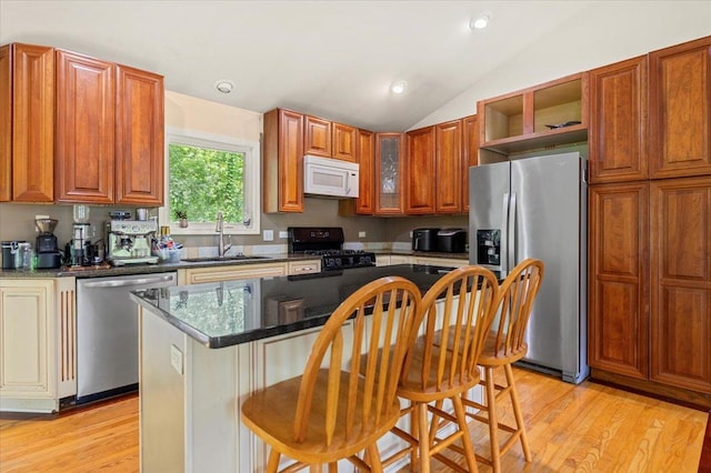 25612 W Woodlawn Ave, Antioch, IL 60002 - kitchen featuring appliances with stainless steel finishes, vaulted ceiling, a kitchen bar, open shelves, and light wood-style flooring