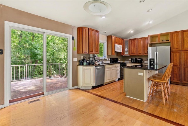25612 W Woodlawn Ave, Antioch, IL 60002 - kitchen featuring stainless steel appliances, light wood-style flooring, open shelves, a breakfast bar area, and lofted ceiling