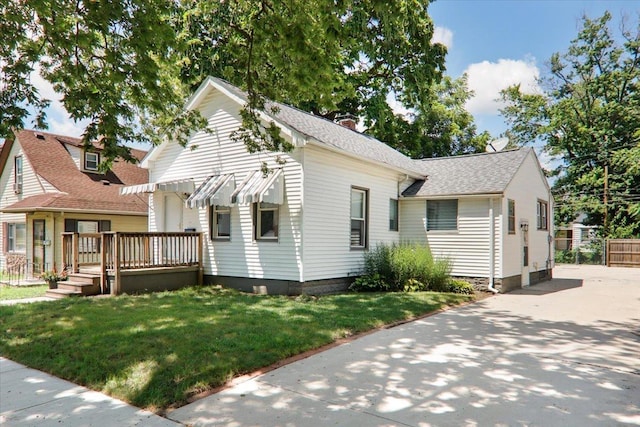 711 W Front St, Bloomington, IL 61701 - view of front of home featuring a front lawn, a wooden deck, a chimney, and a shingled roof