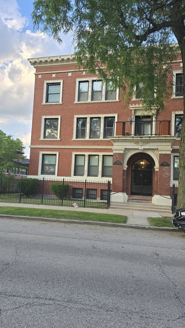 3733 S Lake Park Ave, Chicago, IL 60653 - view of front of home with brick siding, a fenced front yard, and a balcony