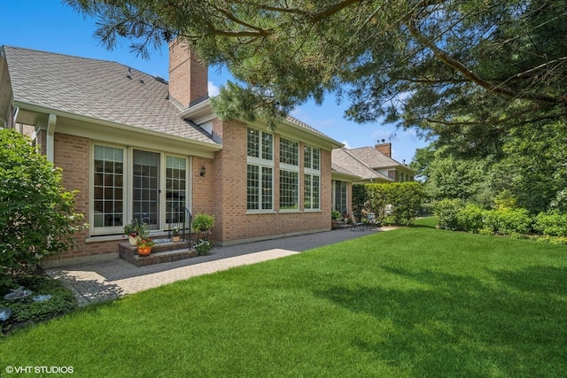 823 Balmoral Ln, Northbrook, IL 60062 - back of property featuring brick siding, a lawn, a chimney, a shingled roof, and a patio area